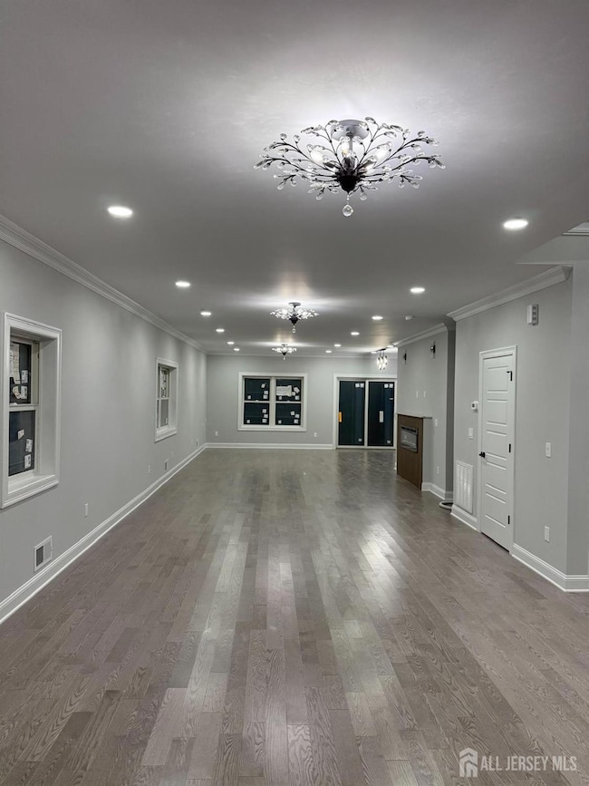 spare room featuring crown molding, recessed lighting, wood finished floors, and a glass covered fireplace