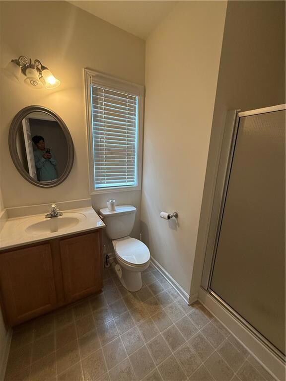 Full bath with vanity, a shower stall, toilet, and baseboards