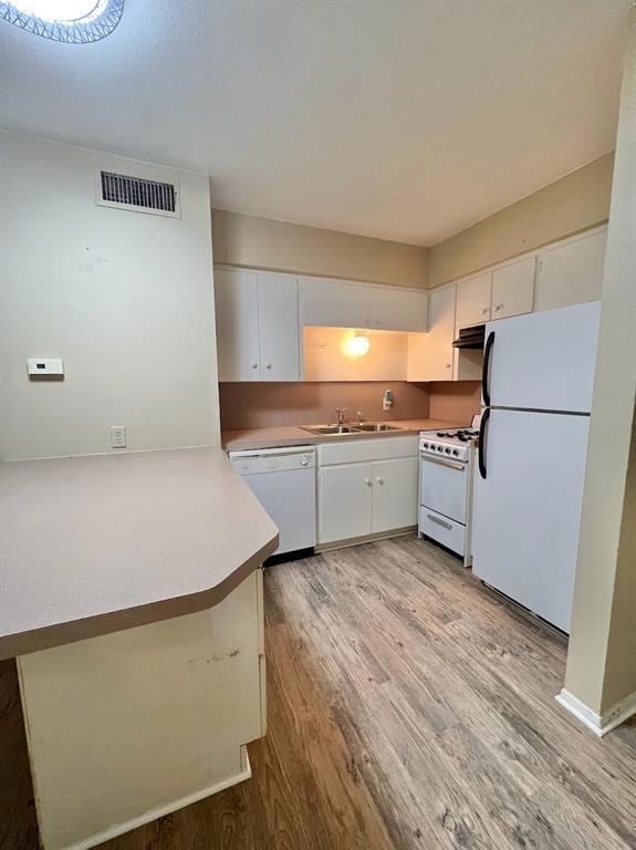 Kitchen featuring a peninsula, white appliances, white cabinetry, and light wood-type flooring