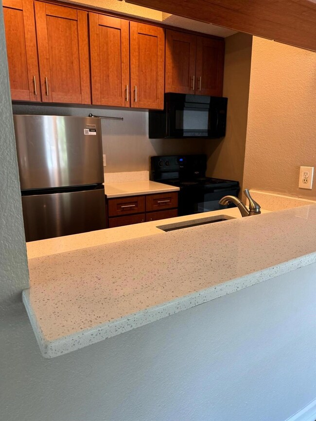 Kitchen featuring black appliances, brown cabinet