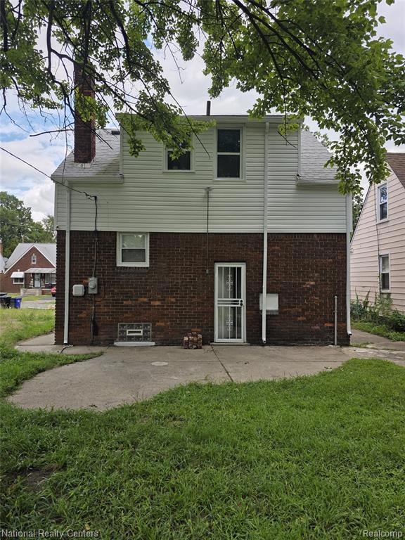 Rear view of house featuring a chimney, brick siding, and a patio area