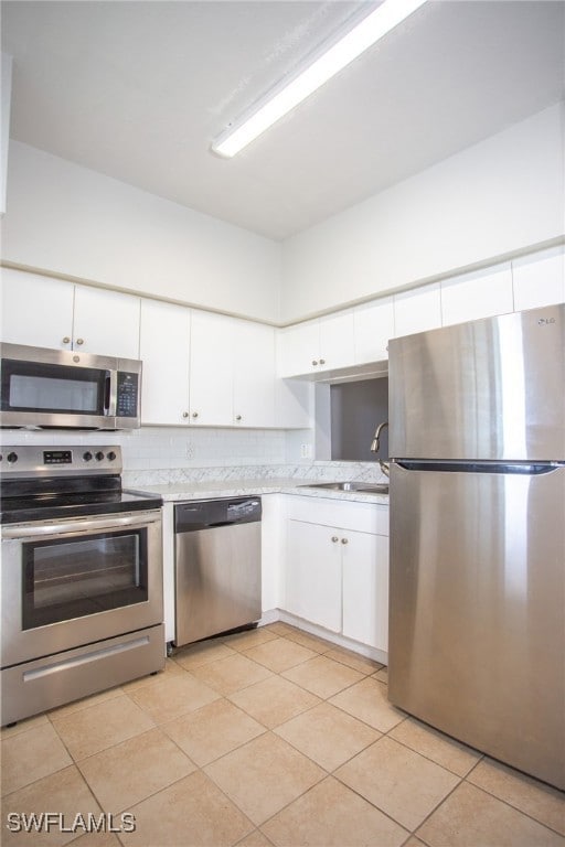 Kitchen with white cabinetry, backsplash, light st