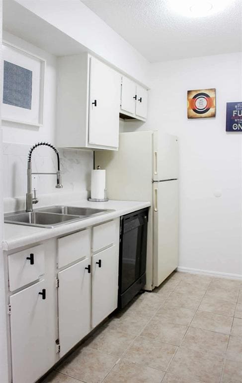 Kitchen featuring light countertops, white cabinets, dishwasher, light tile patterned floors, and a textured ceiling