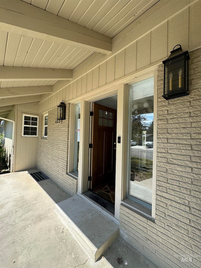 Doorway to property with brick siding and board and batten siding