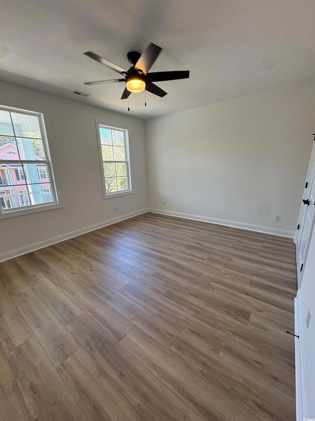 Unfurnished room with baseboards, visible vents, a ceiling fan, and wood finished floors