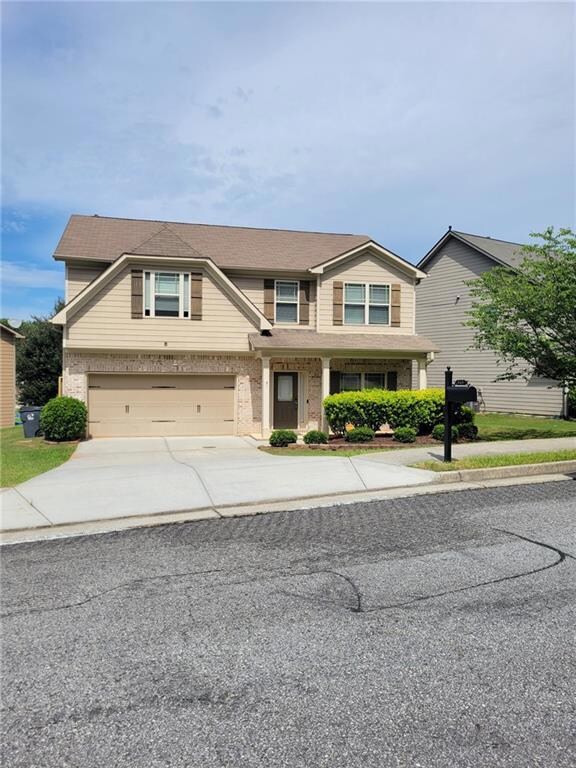 View of front facade featuring concrete driveway, brick siding, and a garage