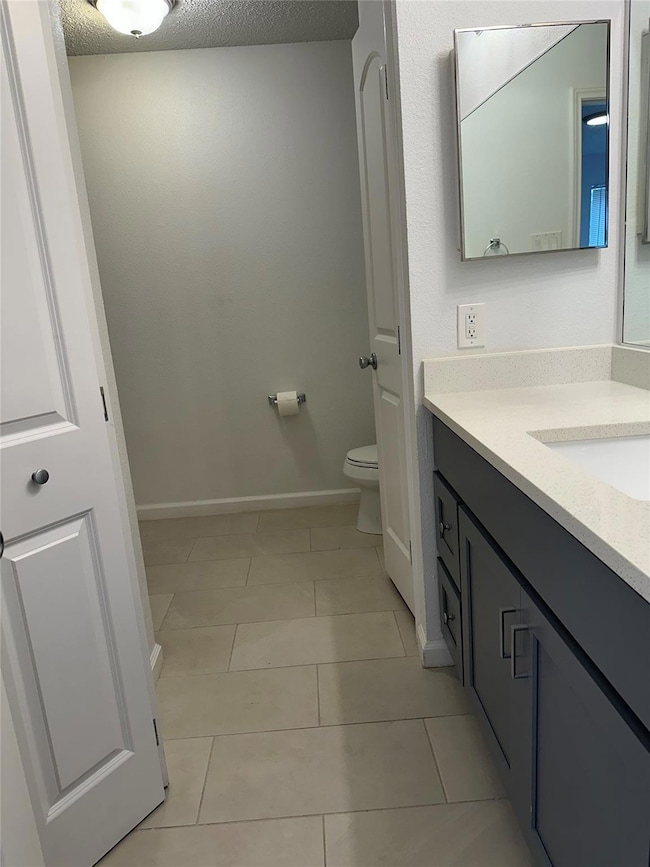 Bathroom with toilet, tile patterned floors, vani