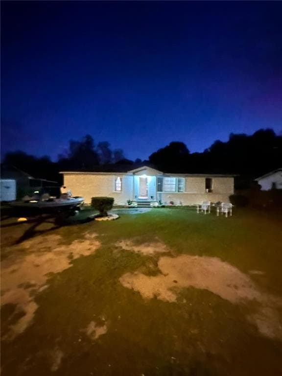 Back of house at night featuring a lawn