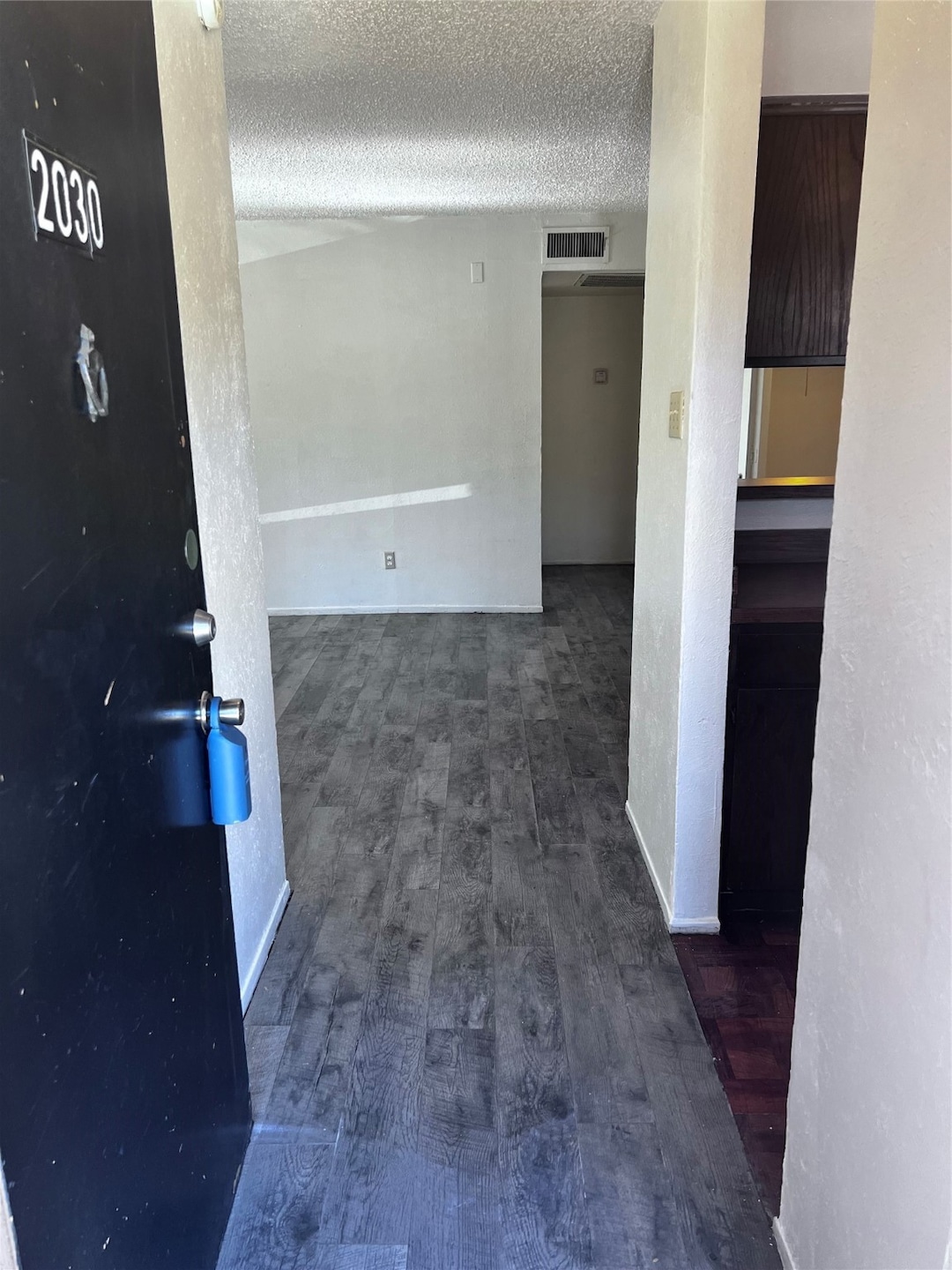 Corridor featuring dark wood-style flooring and a textured ceiling