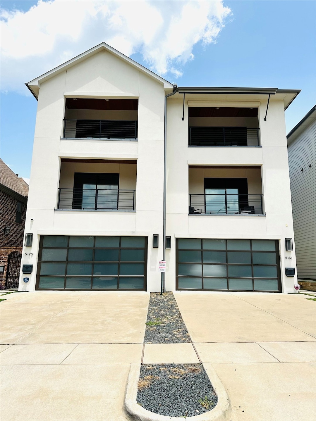 View of front of house with a garage, stucco siding, driveway, and a balcony