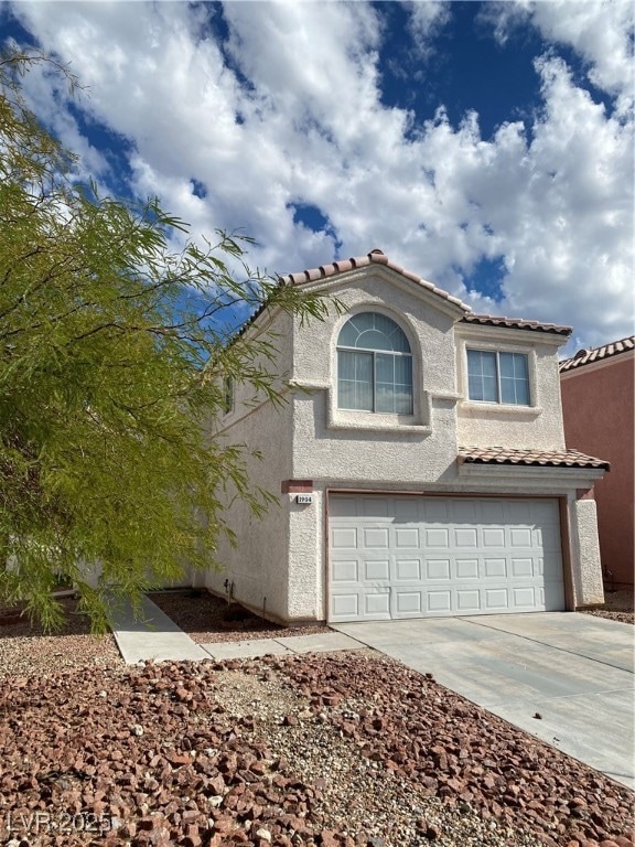 View of front facade with concrete driveway, stucco siding, a tiled roof, and an attached garage