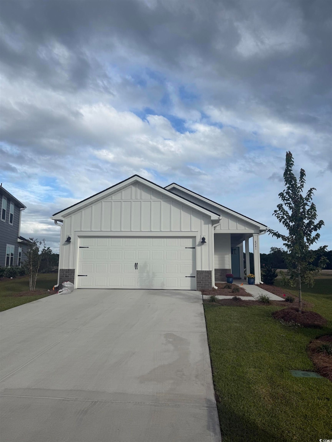View of home's exterior with board and batten siding, driveway, a garage, a lawn, and a porch