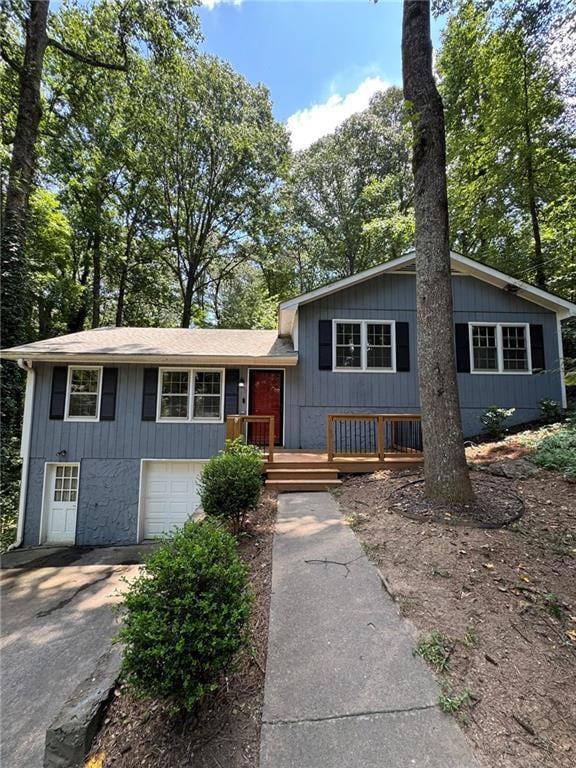 Split level home featuring driveway, an attached garage, and a deck