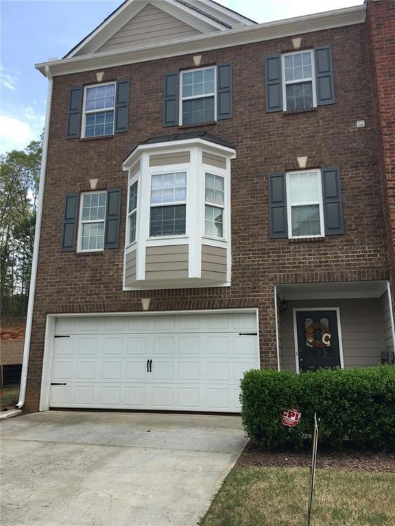 Townhome / multi-family property featuring concrete driveway, a garage, and brick siding