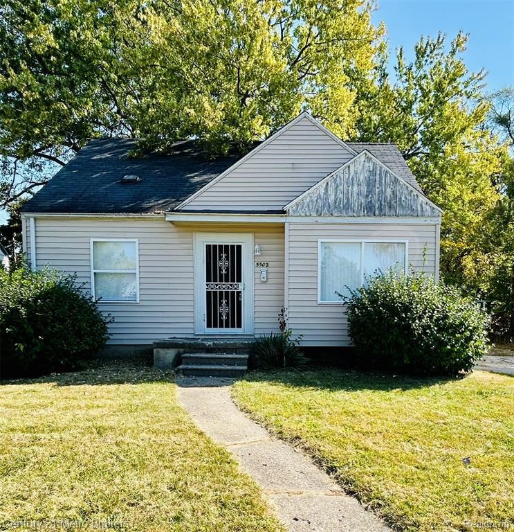 Bungalow-style home with a front lawn, roof with shingles, and entry steps