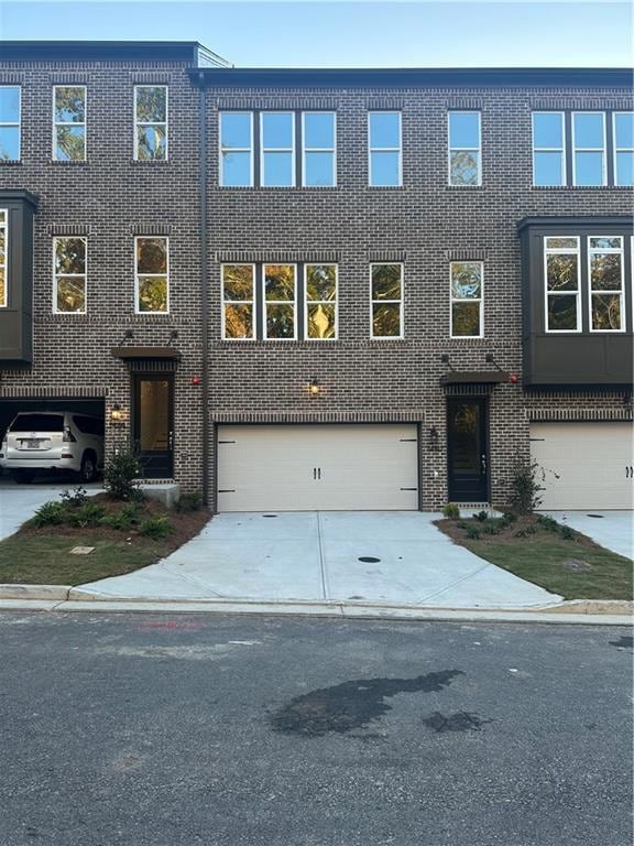 View of front facade with brick siding, concrete driveway, and an attached garage