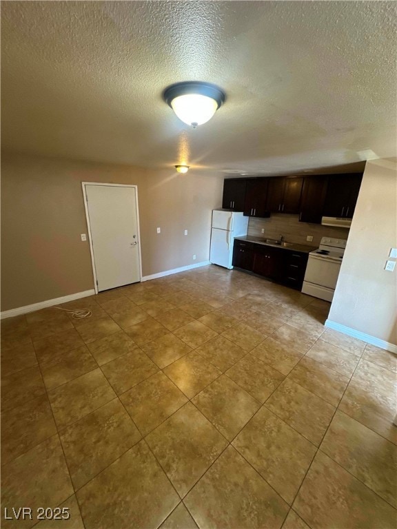 Kitchen featuring white appliances, a textured cei