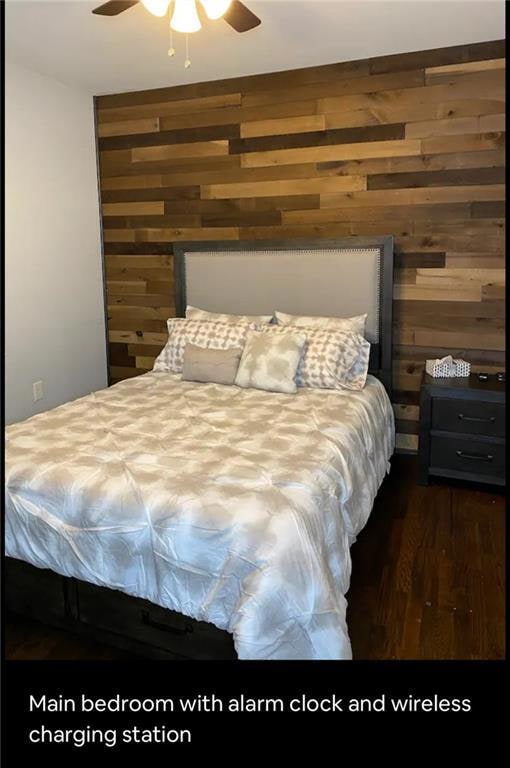 Bedroom featuring wooden walls, wood finished floors, and a ceiling fan