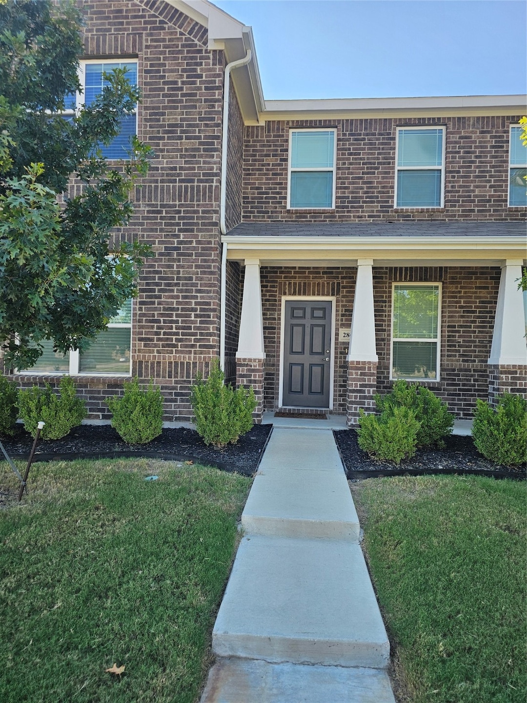 Entrance to property with brick siding and a yard