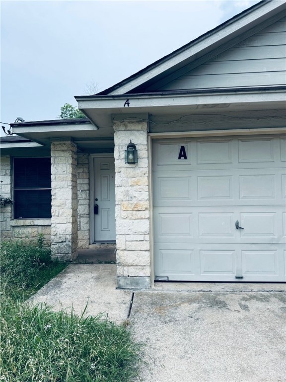 View of exterior entry featuring a garage, stone s