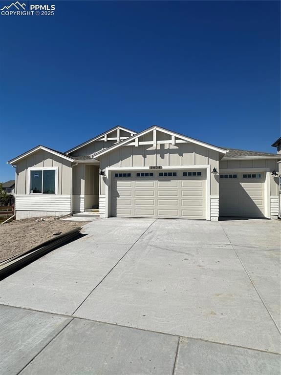 View of front of house featuring board and batten siding, an attached garage, and concrete driveway