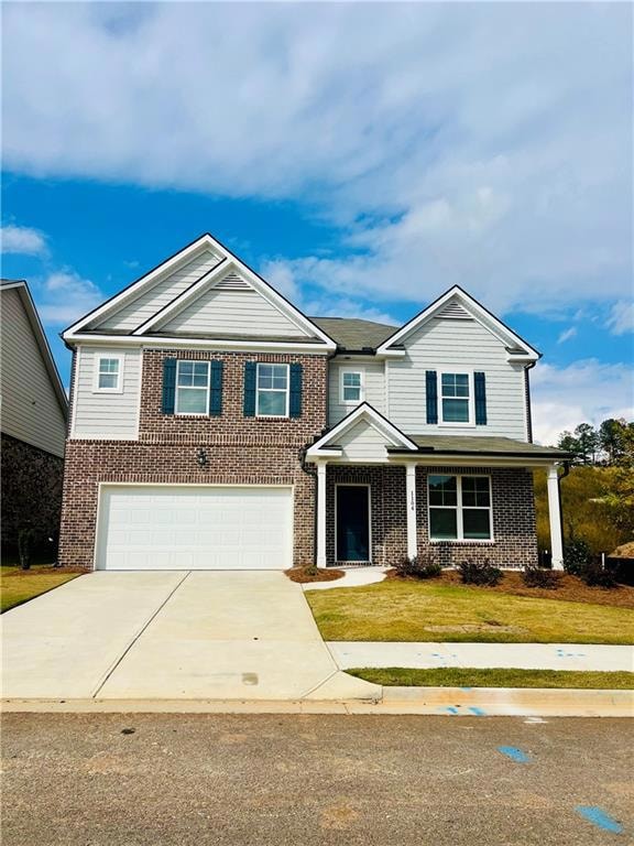 View of front facade featuring driveway, brick siding, covered porch, and a garage
