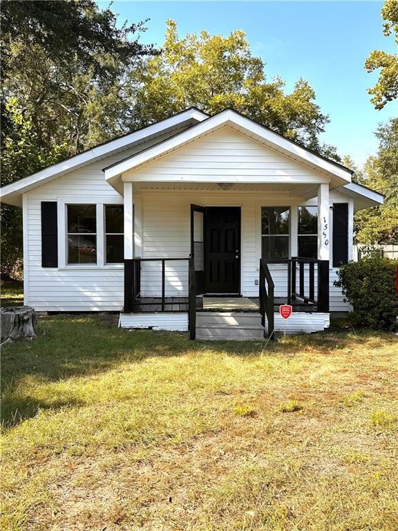 Bungalow featuring covered porch and a front lawn