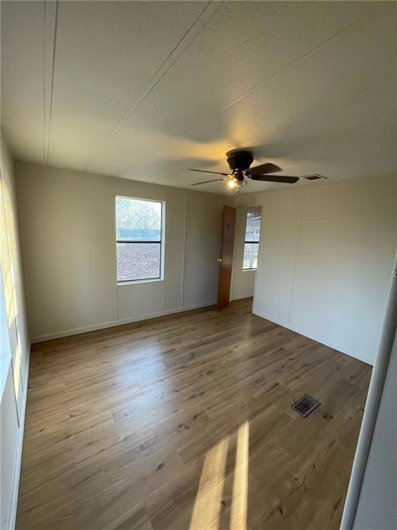Spare room featuring light wood-style flooring, a textured ceiling, and a decorative wall