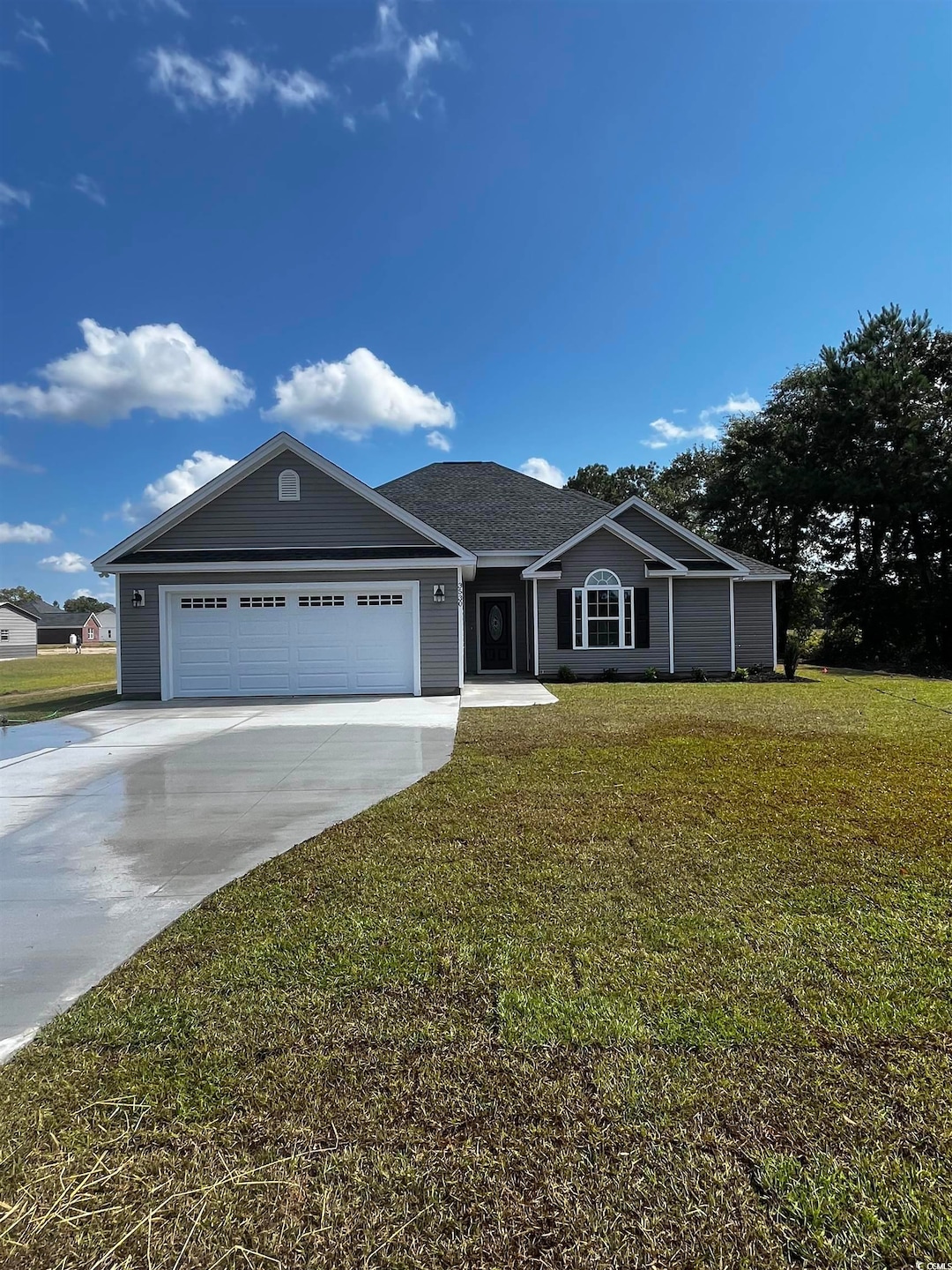 Ranch-style home featuring concrete driveway, a front yard, and a garage