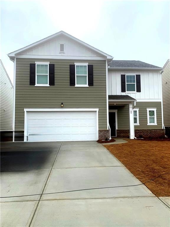 View of front of property featuring board and batten siding, a garage, brick siding, driveway, and roof with shingles