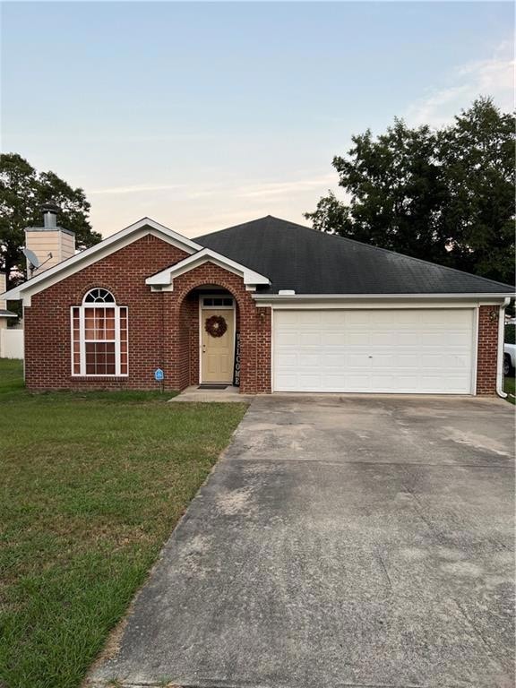 Ranch-style home featuring a garage and a lawn