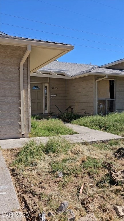 Entrance to property featuring roof with shingles