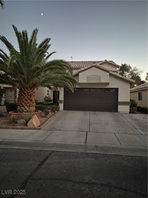 View of front of house featuring stucco siding, concrete driveway, an attached garage, and a tiled roof