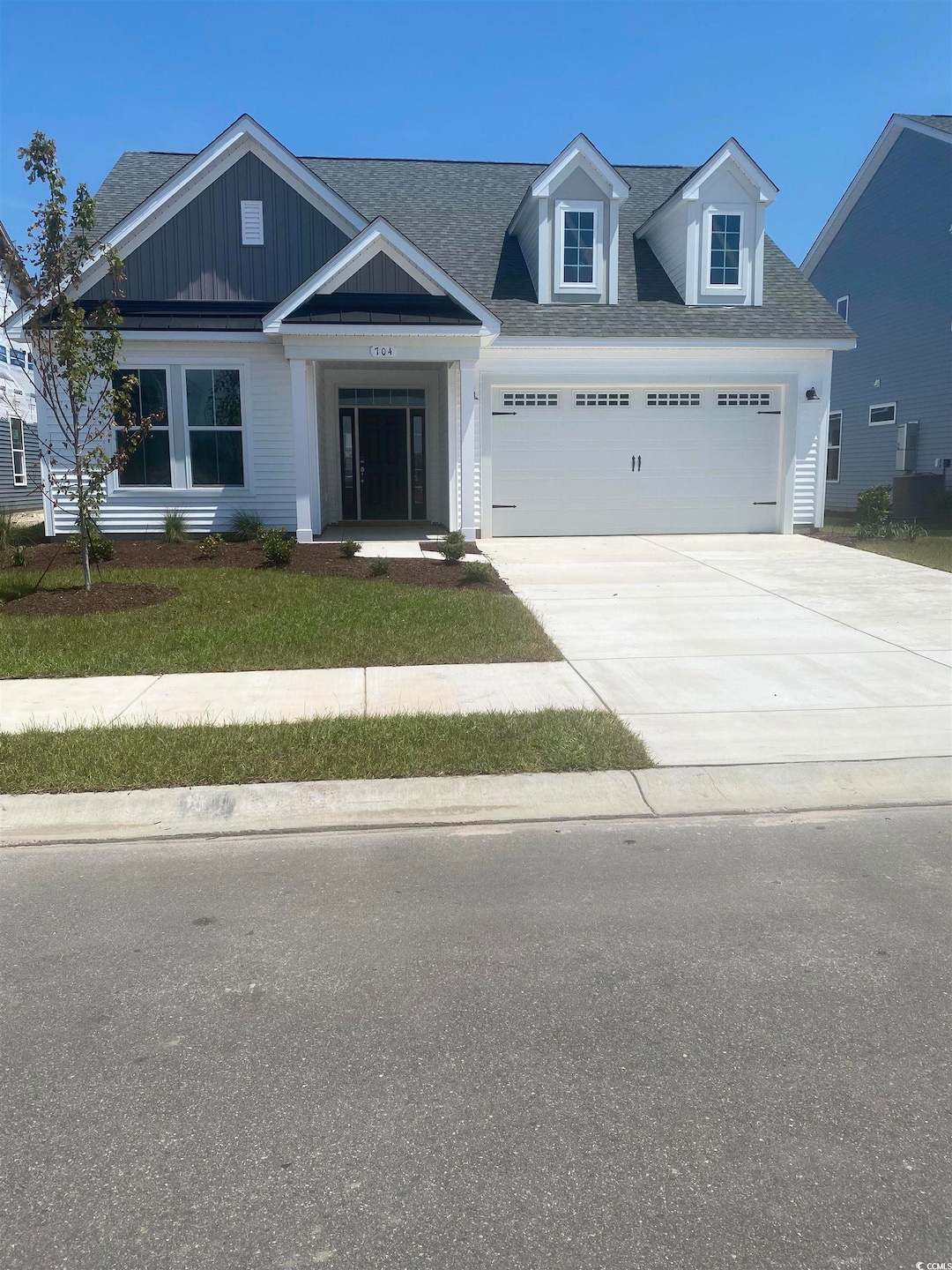 View of front of property featuring concrete driveway, a shingled roof, a garage, a front yard, and board and batten siding