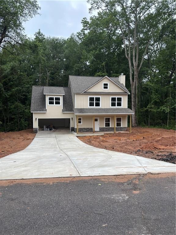 View of front of property with a chimney, concrete driveway, a shingled roof, a garage, and board and batten siding