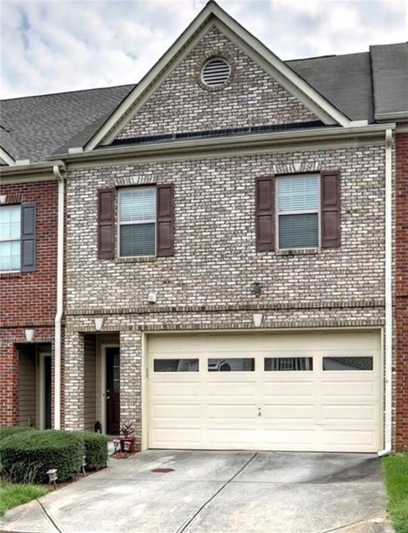 View of front facade featuring driveway, brick siding, and a garage