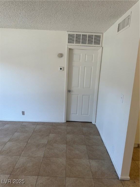 Empty room with visible vents, a textured ceiling,