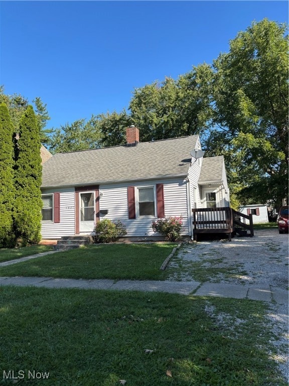 View of front of house with roof with shingles, a front yard, and a chimney