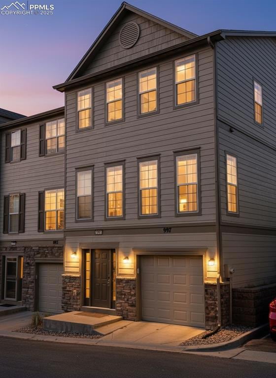 View of front of property featuring stone siding and a garage