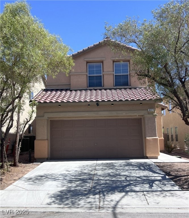 Mediterranean / spanish house featuring a tiled roof, driveway, stucco siding, and an attached garage
