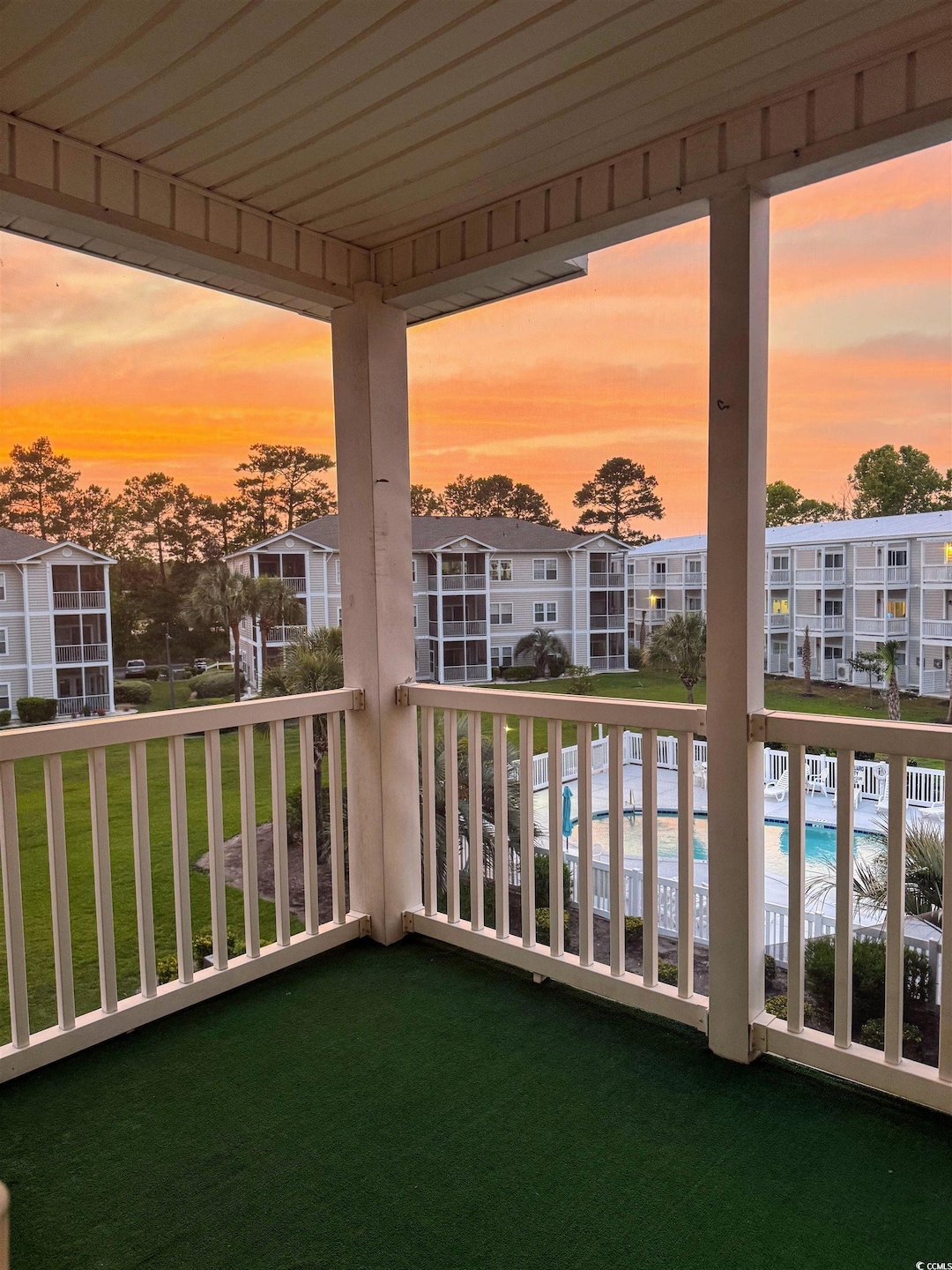 Balcony at dusk featuring view of pool area