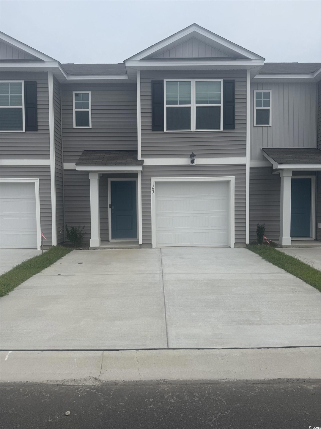 View of front facade featuring board and batten siding, driveway, a garage, and roof with shingles