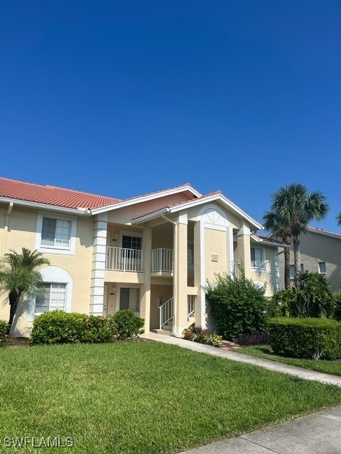 View of front facade with a balcony and a front ya