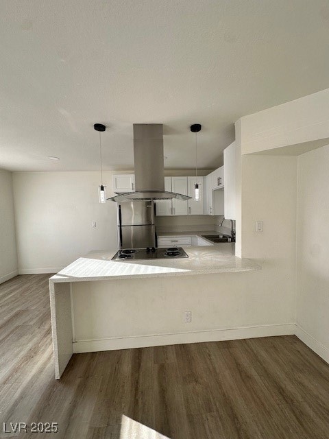 Kitchen with white cabinetry, wall chimney range hood, dark wood-style flooring, pendant lighting, and appliances with stainless steel finishes