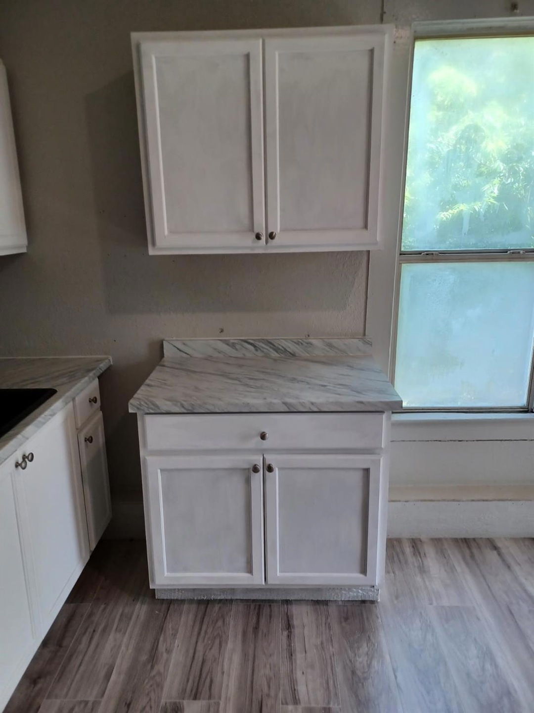 Kitchen featuring white cabinets and light hardwoo