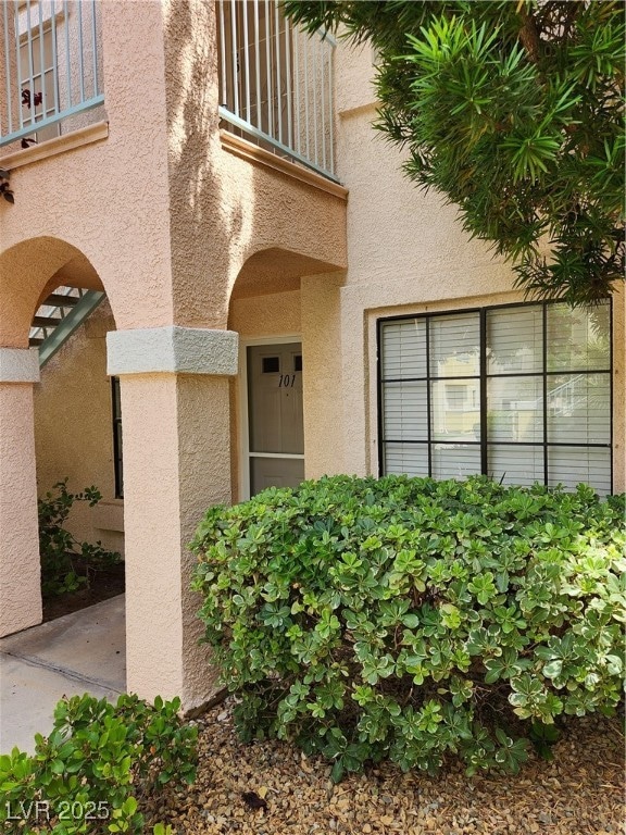 Doorway to property with stucco siding and a balco