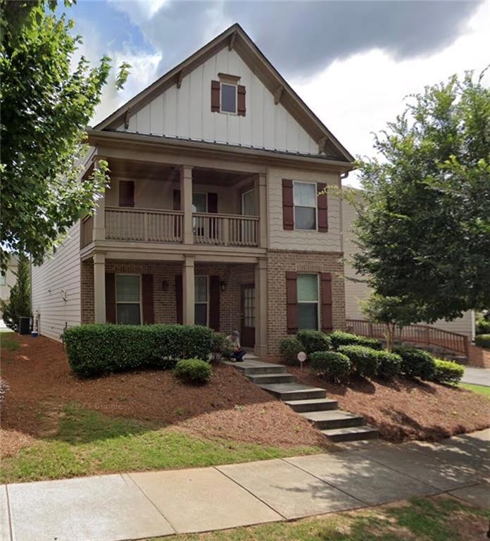 View of front of property with a balcony, brick siding, and board and batten siding