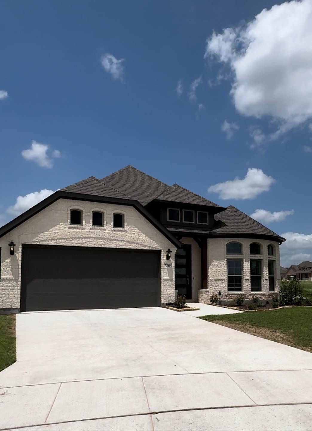 View of front facade featuring concrete driveway, an attached garage, brick siding, and a front yard