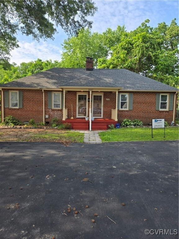 Single story home featuring brick siding, a chimne