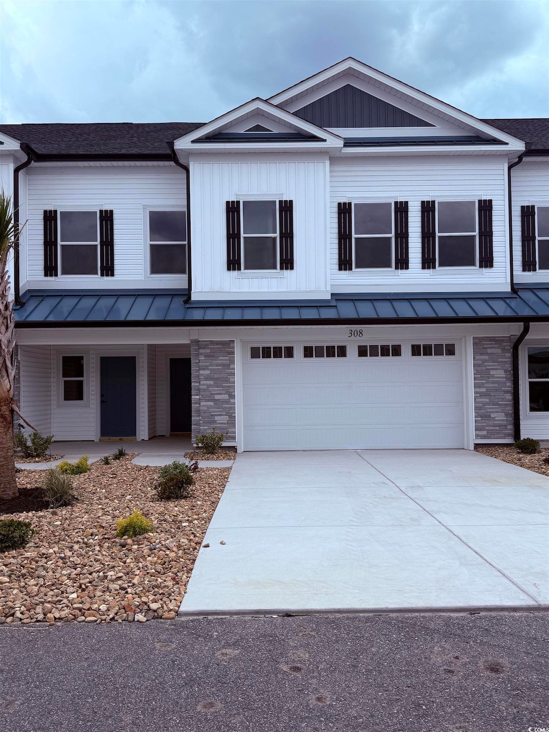 View of front facade with a garage, a porch, drive